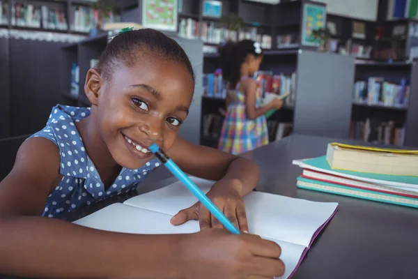 Sorrindo menina estudando na biblioteca — Fotografia de Stock
