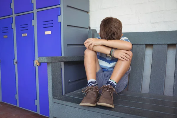 Niño sentado en el banco por casilleros — Foto de Stock