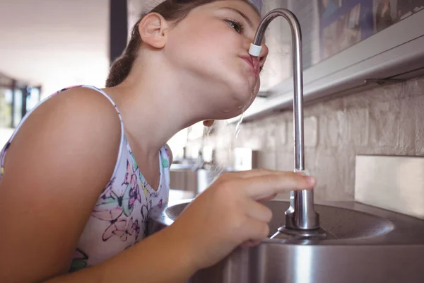 Девушка пьет воду из крана — стоковое фото