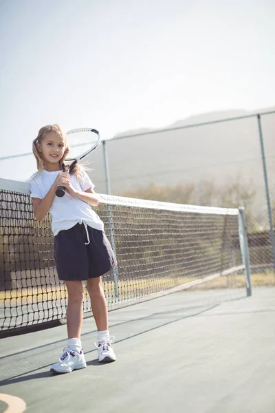 Chica sosteniendo raqueta de tenis mientras está sentado por la red — Foto de Stock