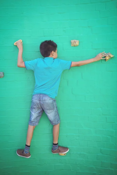 Boy climbing on green wall — Stock Photo, Image