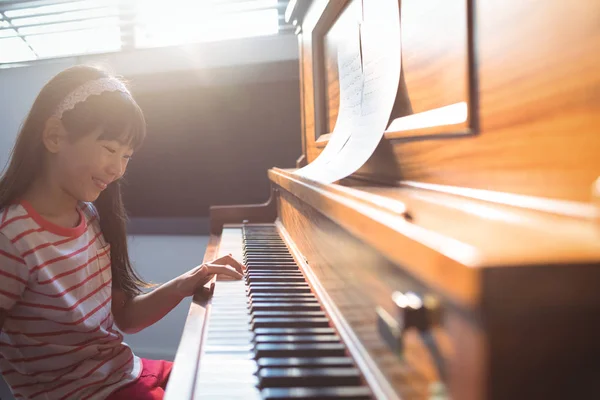 Chica sonriente practicando piano en clase — Foto de Stock