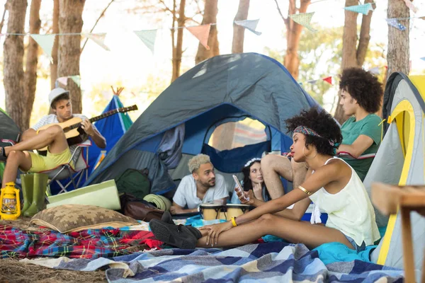 Friends resting while sitting by tent — Stock Photo, Image