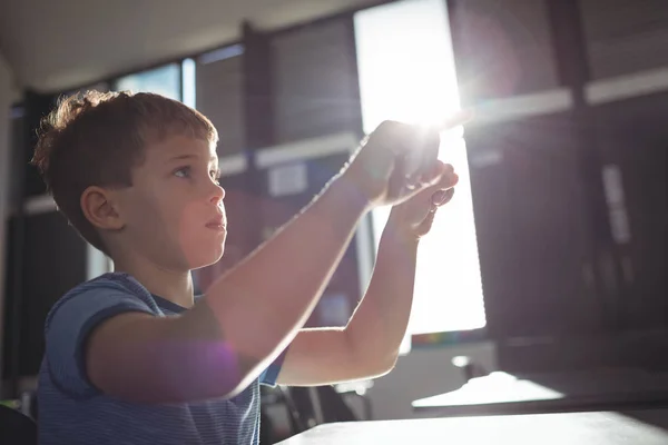 Boy gesturing while sitting at desk — Stock Photo, Image