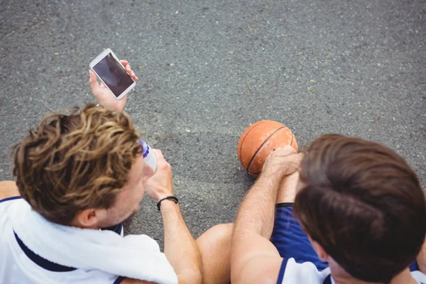Basketball player showing mobile phone to friend — Stock Photo, Image