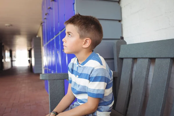 Niño reflexivo sentado en el banco en el pasillo —  Fotos de Stock