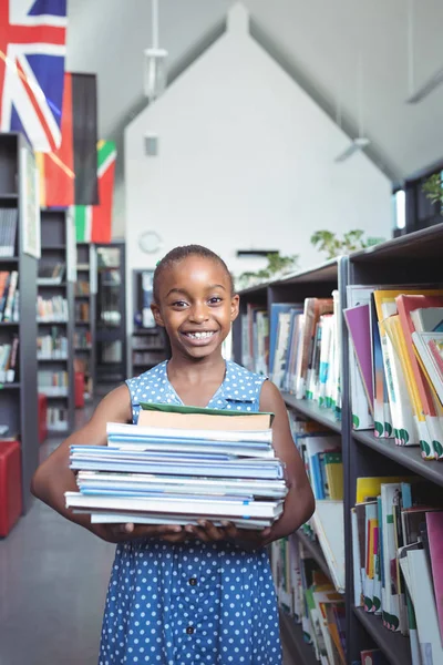 Kitaplığındaki kitap taşırken gülümseyen kız — Stok fotoğraf