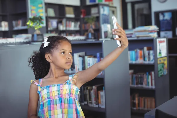 Menina tomando selfie na biblioteca — Fotografia de Stock