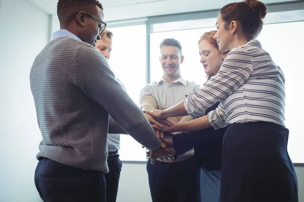 Бізнес-колеги складають руки в офісі — стокове фото