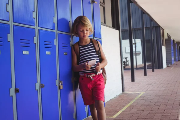 Niño usando el teléfono mientras está de pie junto a taquillas — Foto de Stock