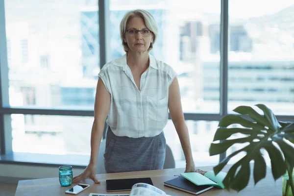 Businesswoman standing by desk — Stock Photo, Image