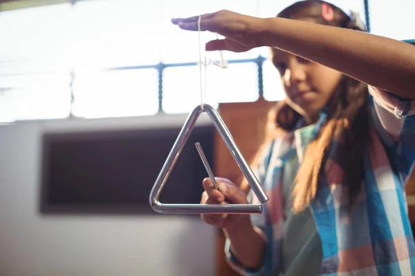 Girl playing triangle in classroom — Stock Photo, Image