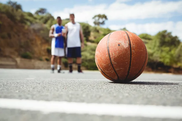 Orange basketball on ground with player — Stock Photo, Image