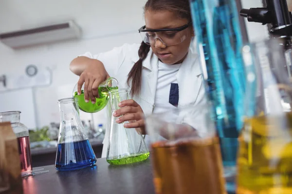 Ученик начальной школы разливает зеленый химикат — стоковое фото