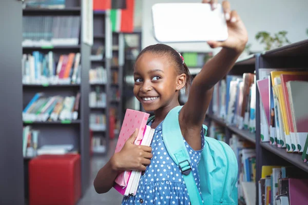 Menina tomando selfie na biblioteca — Fotografia de Stock