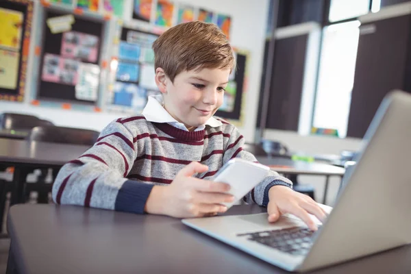 Schoolboy using laptop and  phone — Stock Photo, Image