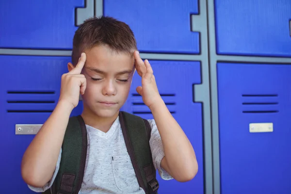 Boy suffering from headache against lockers — Stock Photo, Image