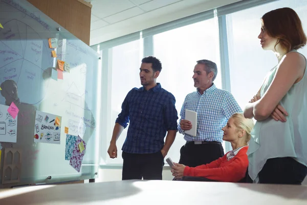 Thoughtful business colleagues looking at whiteboard — Stock Photo, Image