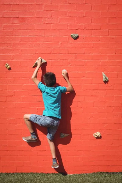 Boy climbing orange wall — Stock Photo, Image