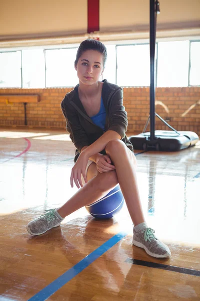 Confident woman sitting on basketball — Stock Photo, Image