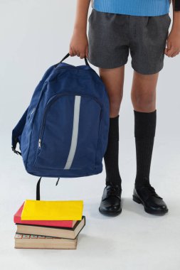 Schoolboy standing with bag and books clipart