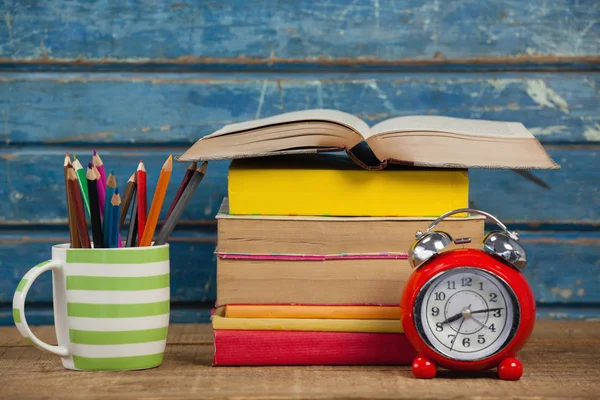 Libros apilados con reloj y porta bolígrafos — Foto de Stock