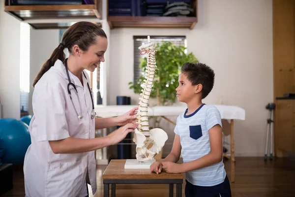 Therapist explaining to boy with artificial spine — Stock Photo, Image
