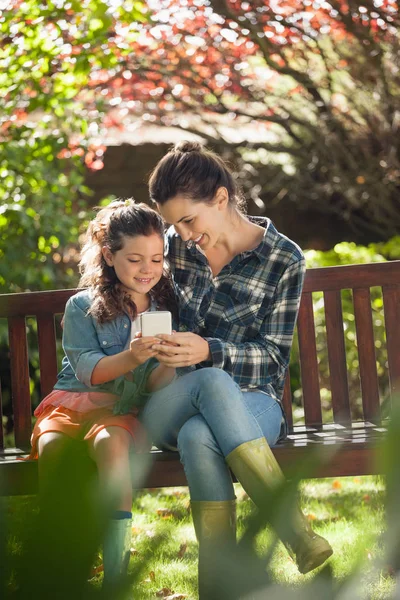 Sonriente niña y madre usando el teléfono móvil —  Fotos de Stock