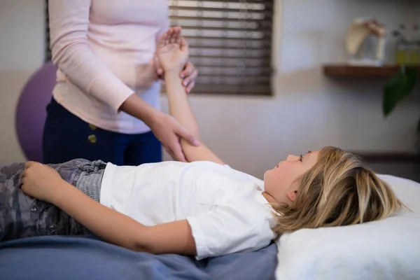 Therapeut untersucht Arm mit Junge — Stockfoto