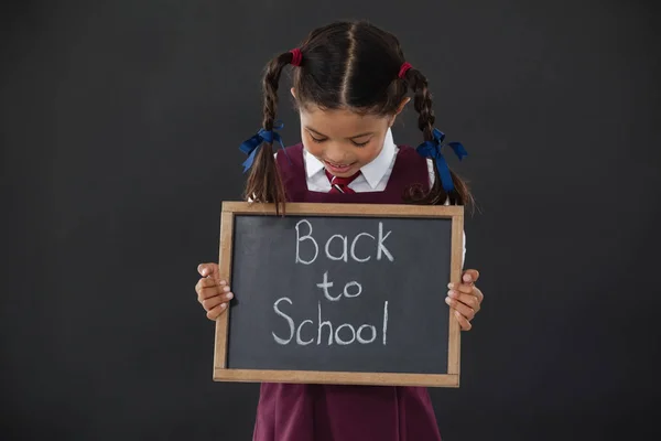 Schoolmeisje bedrijf leisteen met tekst — Stockfoto