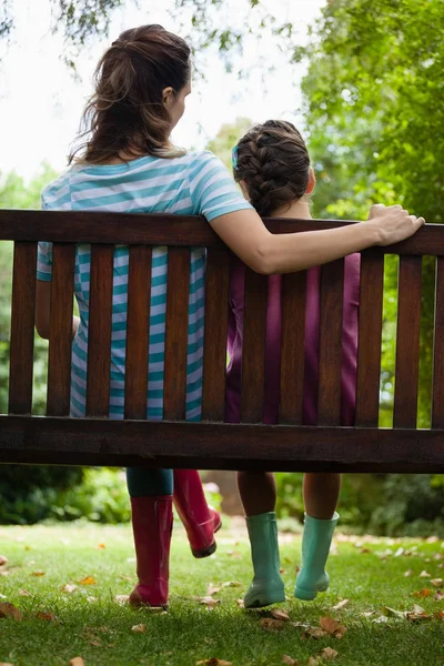 Niña y mujer sentadas en un banco de madera — Foto de Stock