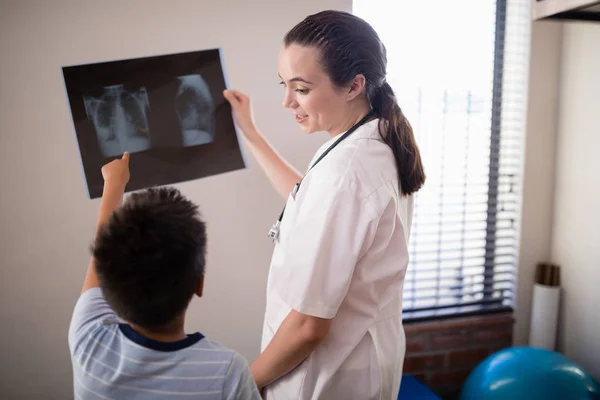 Terapeuten tittar på pojken som pekar mot röntgen — Stockfoto