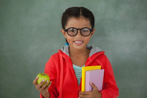 Młoda dziewczyna trzyma jabłko i książek — Zdjęcie stockowe