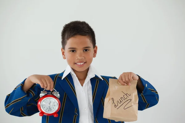 Skolpojke holding klocka och lunch väska — Stockfoto
