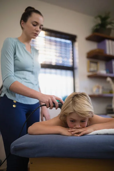 Thérapeute féminine utilisant l'échographie sur le dos du garçon — Photo