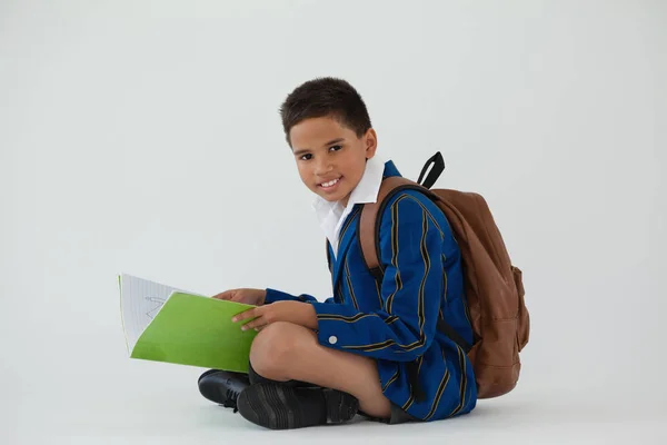 Skolpojke sitter och håller bok — Stockfoto