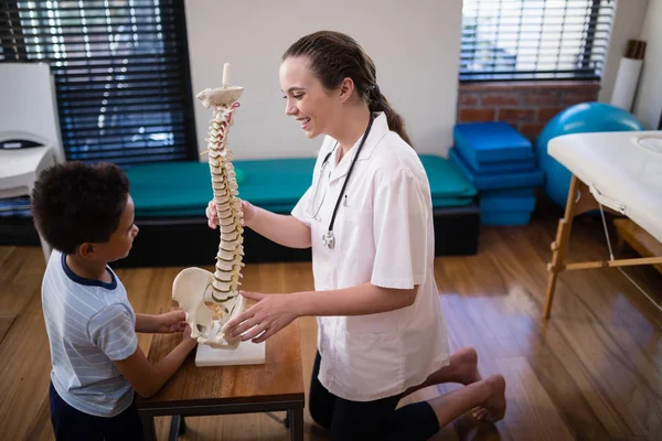 Therapist explaining boy with artificial spine — Stock Photo, Image