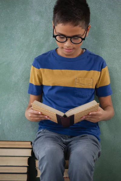 Uczniak siedzi na stos książek — Zdjęcie stockowe
