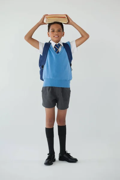 Colegial sosteniendo libros en la cabeza — Foto de Stock