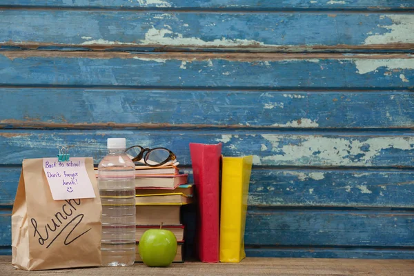 Stacked books with apple and lunch bag — Stock Photo, Image