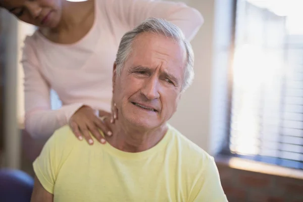 Patient fronçant les sourcils tout en recevant un massage du cou — Photo