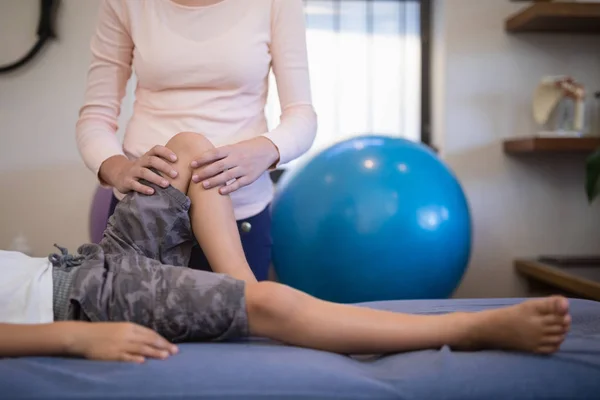 Terapeut masserande knäet av pojke — Stockfoto