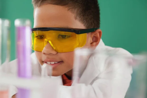 Schoolboy experimenting with vessels — Stock Photo, Image