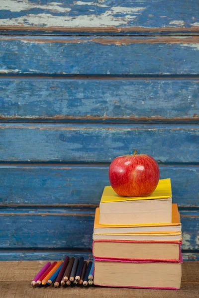 用苹果和彩色铅笔堆积的书 — 图库照片