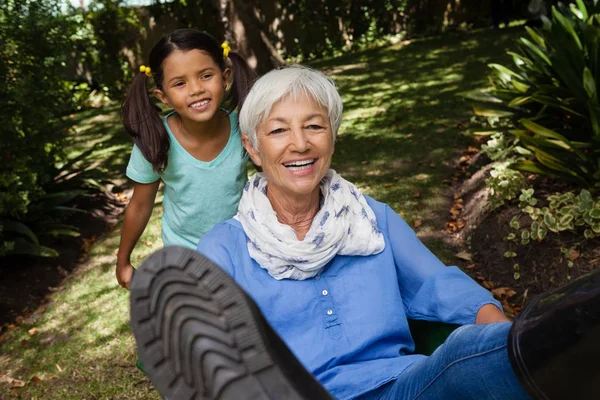 Chica empujando alegre abuela en carretilla —  Fotos de Stock