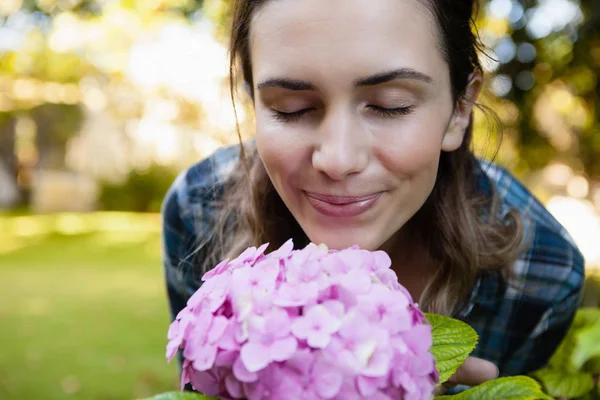 Donna che odora di fiori di ortensia viola — Foto Stock