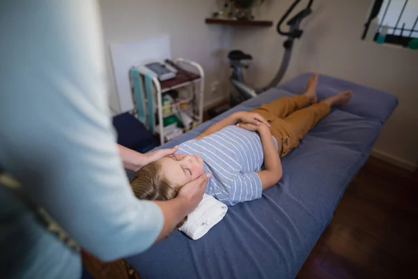 Physiotherapist giving head massage to boy — Stock Photo, Image