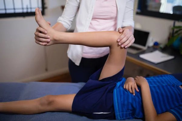 Терапевт масажує коліно з хлопчиком — стокове фото