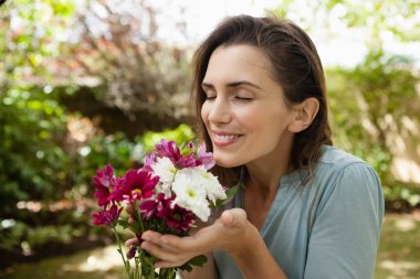 woman with closed eyes smelling flowers clipart