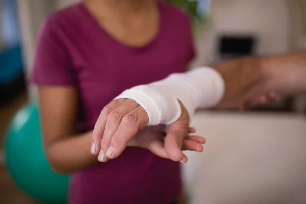 Patientin mit Verband am Handgelenk von Therapeutin — Stockfoto